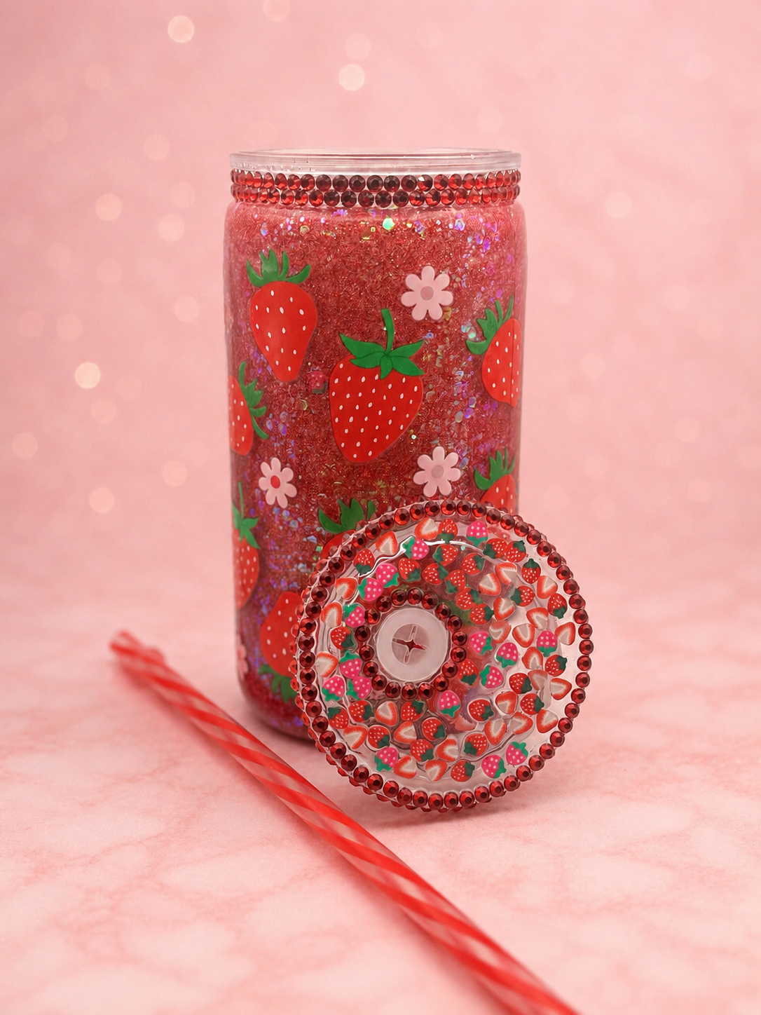 16oz strawberry snow globe tumbler with red glitter, strawberry and daisy design, red rhinestones, decorated strawberry lid and reusable striped straw.